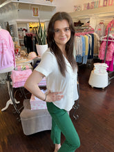 Woman wearing a white short sleeve blouse while standing in a store.