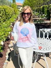 Woman wearing a 'Summer Vibes' shirt with a shell design outdoors.