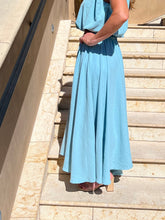 Person wearing a light blue dress standing on stone steps.