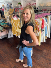 Woman in a clothing store wearing a black top showing side view.