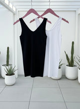 Black and white tank tops on hangers with potted plants in the background