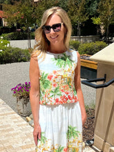 Woman wearing a floral top standing outdoors with trees and plants in the background