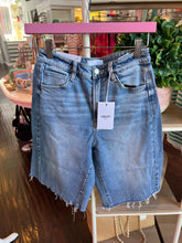 Blue denim shorts with a visible brand tag on a store shelf.