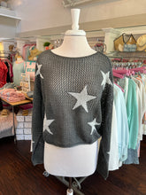 Mannequin wearing a gray sweater with white star patterns in a store setting.