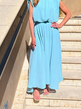 Person wear light blue skirt standing on a staircase outdoors.
