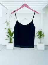 Black spaghetti strap top on a pink hanger with a white background