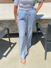 Person wearing light blue checkered pants and a white top outdoors.