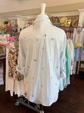Mannequin wearing a striped shirt with decorative elements in a store setting