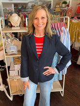 Woman wearing a navy blue textured blazer standing in a clothing store