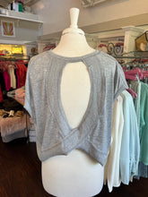 Gray tank top on a mannequin in a store setting with clothing racks in the background.