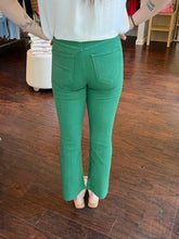 Woman wearing green jeans facing backwards standing in a store.