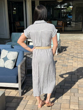 Woman in a striped dress standing on a patio with outdoor furniture.