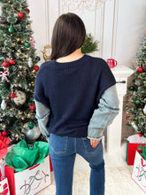 Woman wearing an Americana denim sleeved sweater in a festive room with a Christmas tree.