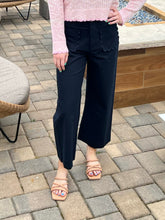 Person wearing a pink sweater and navy pants on a patio