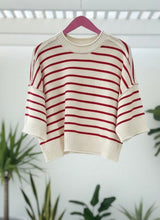 Red Striped sweater on a hanger with a plant in the background