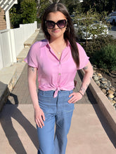 Woman wearing a lilac top and sunglasses outdoors on a sunny day.