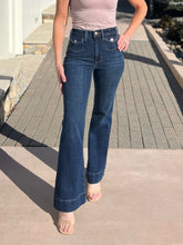 Person wearing blue flared jeans standing on a sidewalk.