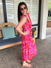 Woman in a pink floral dress standing on a patio