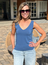 Woman wearing a blue tank top and sunglasses outdoors