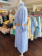 Blue shirt dress with a woven tan belt showing side view on a mannequin in a clothing store