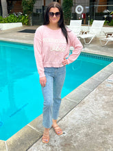 Woman in pink sweatshirt and jeans standing by a pool