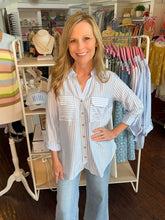 Woman wearing a light blue and white striped shirt in a clothing store