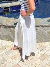 Person wearing a white skirt and striped top by a poolside.