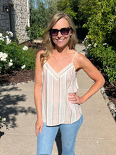 Woman wearing a striped tank top and sunglasses outdoors.