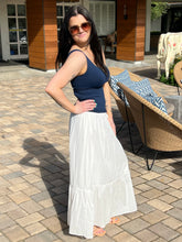 Woman in a blue top and white skirt standing on a patio