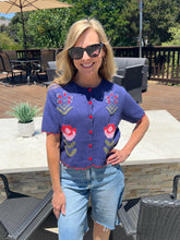 Woman wearing a floral sweater and sunglasses outdoors on a patio