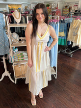 Woman in a white dress with yellow accents standing in a clothing store.