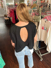 Woman wearing a black top with an open back in a clothing store.