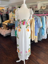 Floral dress showing the back view on a mannequin in a clothing store with racks of clothes in the background.