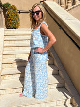 Woman in a blue floral top and pant standing on stone steps outdoors