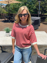 Woman wearing a red and white striped shirt and sunglasses outdoors on a patio.