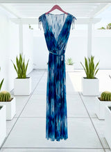 Blue print jumpsuit hanging on a patio with a few plants.