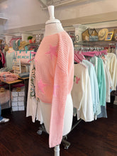 Mannequin wearing a pink knitted sweater with a pattern in a store setting.