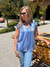 Woman wearing a blue striped shirt and sunglasses outdoors.