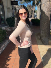 Woman wearing sunglasses and a khaki tee on a sunny day outdoors. 