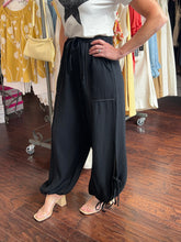 Person wearing black balloon pants in a clothing store.