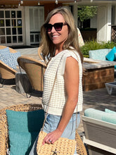 Woman standing outdoors in a patio area with furniture and plants.