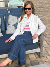 Woman sitting on a blue outdoor sofa wearing sunglasses and a white jacket.