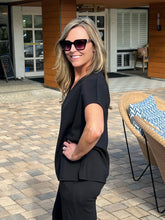 Woman in a black outfit standing outdoors on a patio