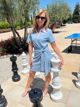 Woman standing next to oversized outdoor chess pieces in a park-like setting
