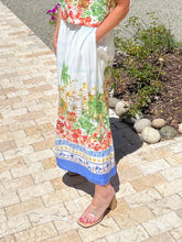 Person wearing a colorful skirt with a scenic print on a paved walkway.