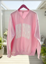 Pink sweatshirt with 'MS FAB' text on a hanger indoors