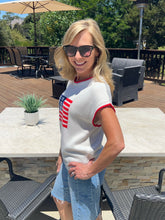 Woman wearing a white t-shirt with an American flag design outdoors on a patio.