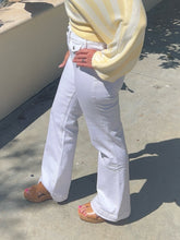 Person wearing a yellow sweater and white pants on a concrete surface