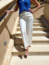 Person wearing a blue top and white pants walking up stone steps.
