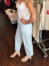 Person wearing a white tank top and light blue pants in a store setting.